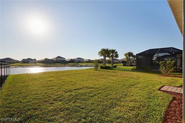 view of yard featuring a lanai, a residential view, and a water view