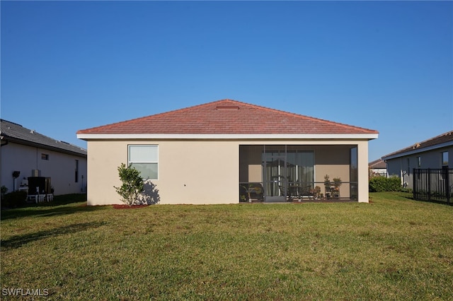 back of house with a yard, a sunroom, and stucco siding