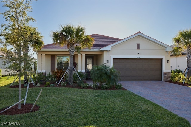 view of front of property with stucco siding, decorative driveway, a front lawn, and an attached garage