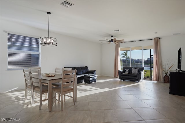 tiled dining space featuring visible vents, baseboards, and ceiling fan with notable chandelier