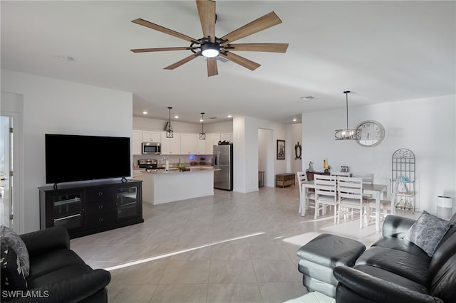 living area with light tile patterned floors, recessed lighting, ceiling fan with notable chandelier, and visible vents