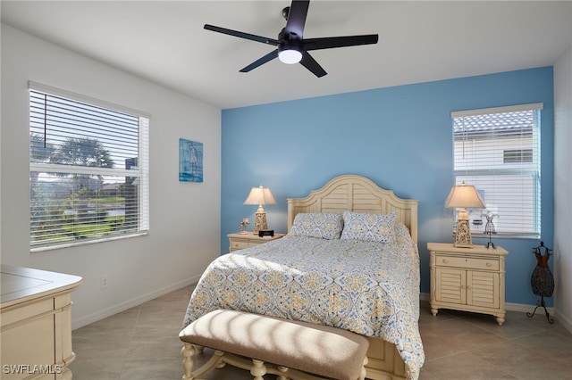 bedroom featuring light tile patterned floors, baseboards, multiple windows, and a ceiling fan