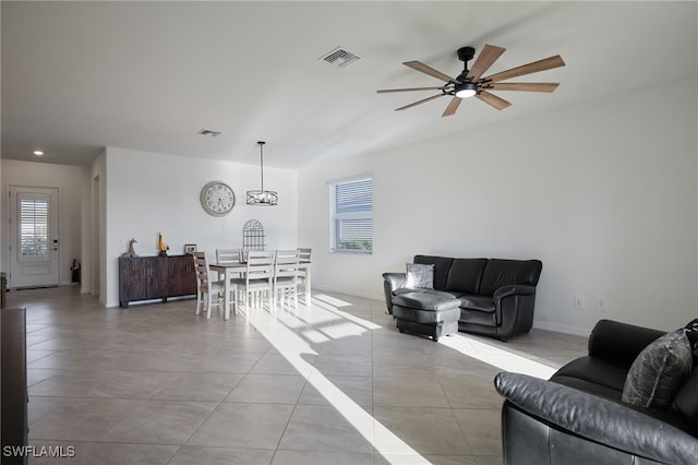 living area featuring tile patterned floors, visible vents, baseboards, and a ceiling fan