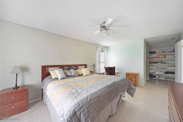 bedroom featuring a spacious closet, light tile patterned floors, a closet, a textured ceiling, and a ceiling fan