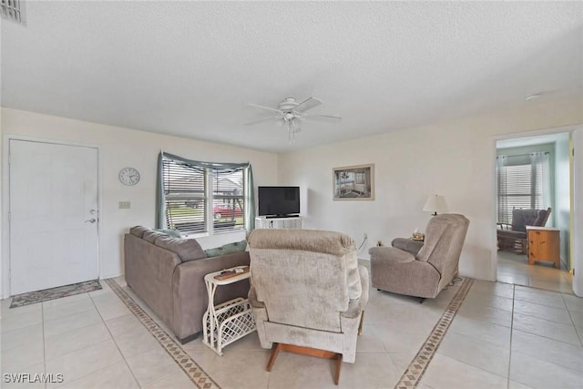 living room with light tile patterned flooring, ceiling fan, a textured ceiling, and a wealth of natural light