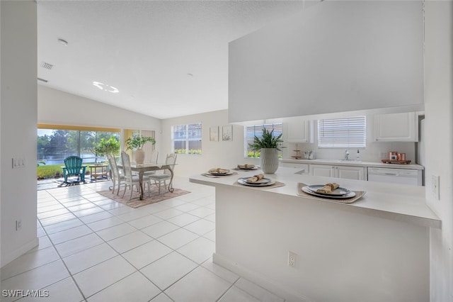 kitchen featuring light tile patterned flooring, white dishwasher, a peninsula, white cabinetry, and light countertops