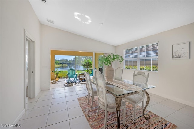 dining room with light tile patterned flooring, visible vents, lofted ceiling, and baseboards