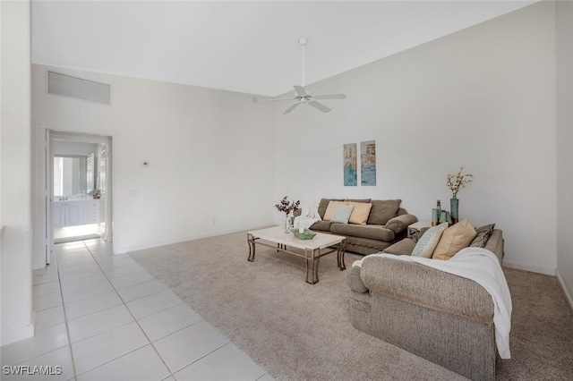 living area with light tile patterned floors, ceiling fan, light carpet, visible vents, and high vaulted ceiling