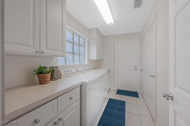 washroom with visible vents, cabinet space, light tile patterned flooring, and washing machine and dryer