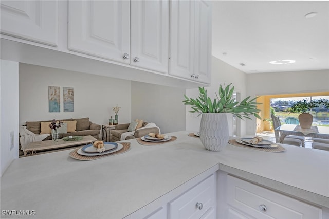 kitchen with open floor plan, white cabinetry, and light countertops