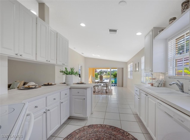 kitchen featuring a sink, visible vents, vaulted ceiling, light countertops, and dishwasher