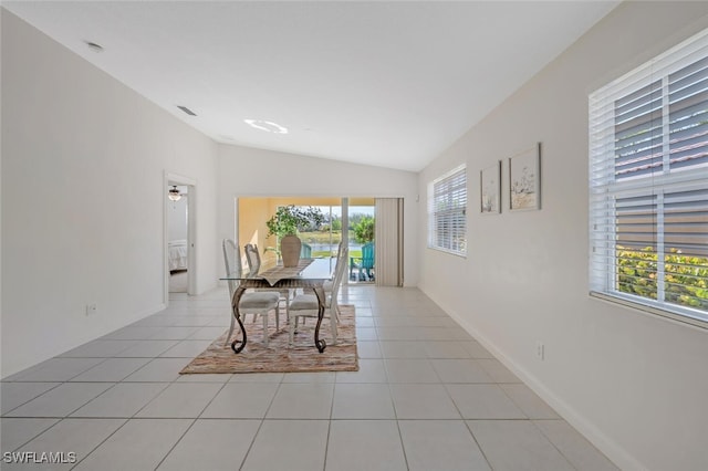 dining space featuring baseboards, light tile patterned floors, and vaulted ceiling