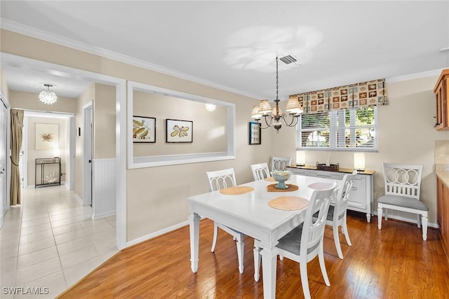 dining room featuring visible vents, crown molding, baseboards, a chandelier, and light wood-style floors