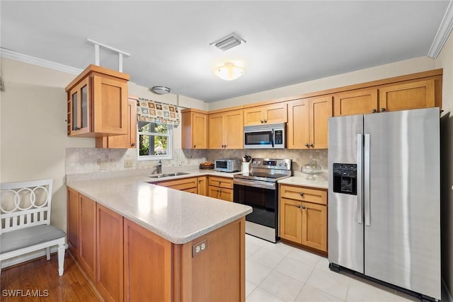 kitchen with visible vents, a peninsula, a sink, decorative backsplash, and appliances with stainless steel finishes