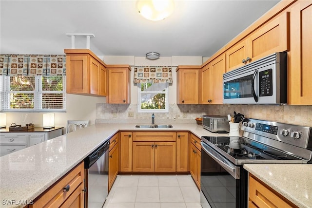 kitchen featuring light stone counters, tasteful backsplash, appliances with stainless steel finishes, and a sink