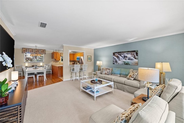 carpeted living area featuring crown molding, baseboards, and visible vents