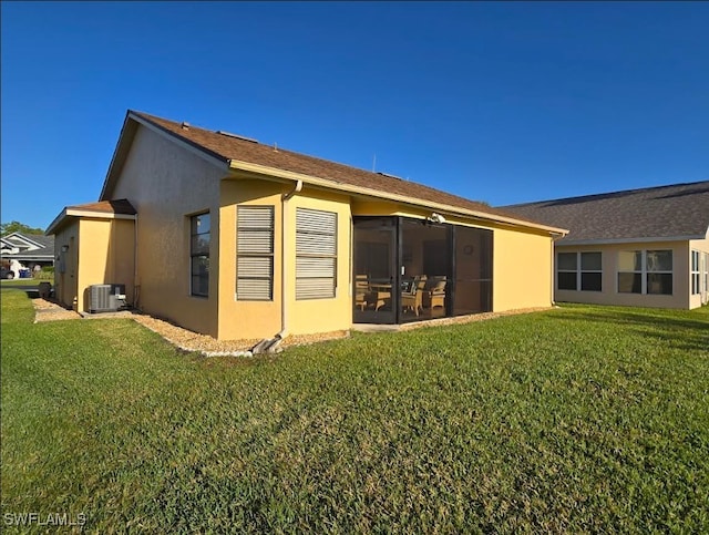 rear view of property with stucco siding, a yard, cooling unit, and a sunroom