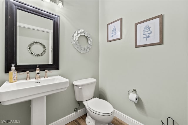 bathroom with a sink, baseboards, toilet, and wood finished floors