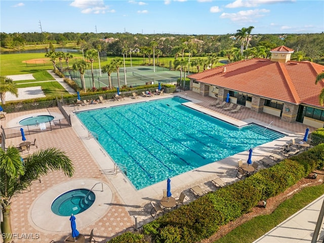 community pool with a hot tub, a patio, and fence