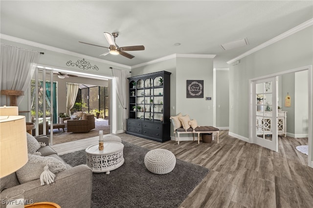 living room featuring baseboards, wood finished floors, ceiling fan, and crown molding