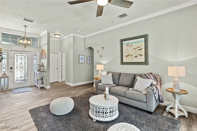 living area with visible vents, ornamental molding, and wood finished floors