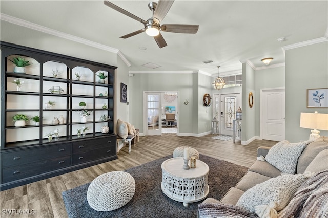 living area featuring baseboards, wood finished floors, a ceiling fan, and ornamental molding