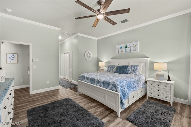 bedroom with visible vents, crown molding, baseboards, wood finished floors, and a closet