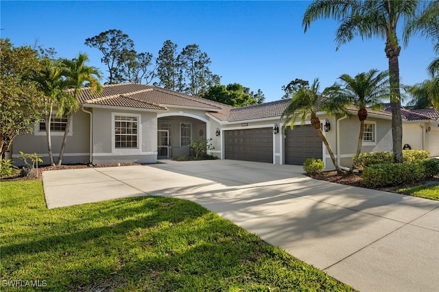 mediterranean / spanish home featuring a front lawn, a tile roof, concrete driveway, stucco siding, and an attached garage