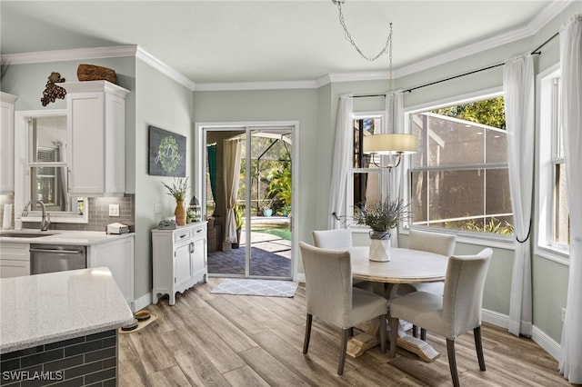 dining room with crown molding, light wood-style flooring, and baseboards