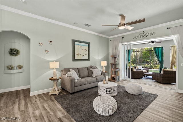 living room with crown molding, wood finished floors, baseboards, and ceiling fan