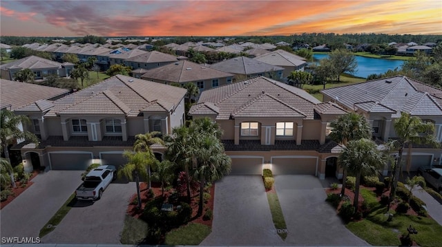 aerial view at dusk with a residential view and a water view