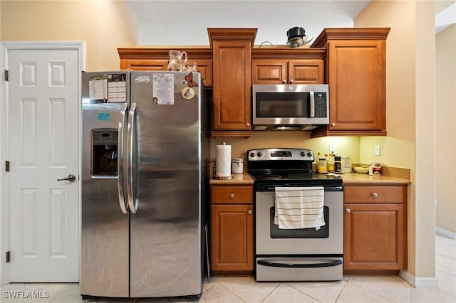 kitchen featuring light tile patterned flooring, brown cabinets, and appliances with stainless steel finishes