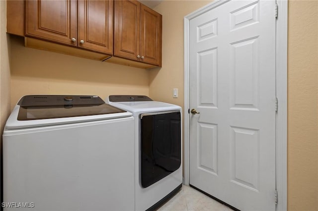 clothes washing area with light tile patterned flooring, cabinet space, and separate washer and dryer