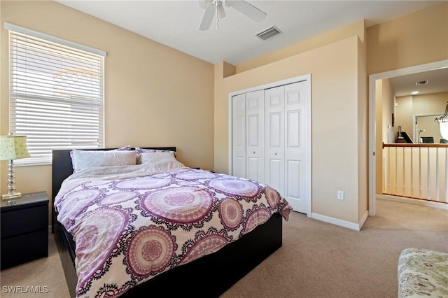 bedroom featuring baseboards, visible vents, ceiling fan, a closet, and light carpet