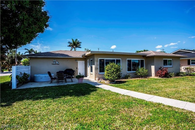 rear view of property featuring a patio, a yard, and stucco siding