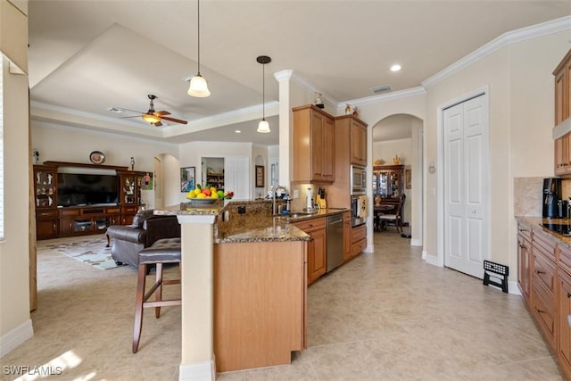 kitchen with a breakfast bar, stone countertops, open floor plan, arched walkways, and appliances with stainless steel finishes