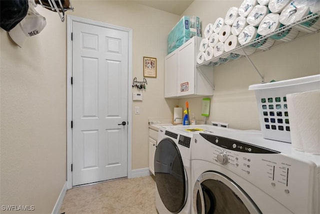 washroom with baseboards, cabinet space, and washing machine and clothes dryer