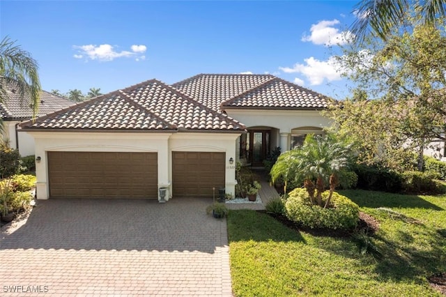 mediterranean / spanish-style house featuring a garage, decorative driveway, a tile roof, and stucco siding