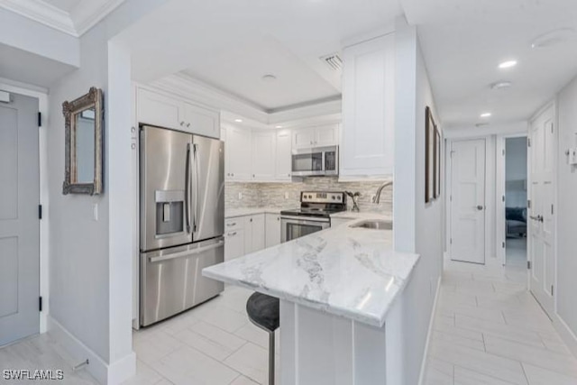 kitchen with a sink, a peninsula, appliances with stainless steel finishes, and white cabinets