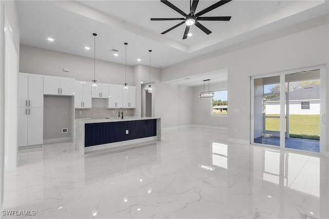 unfurnished living room with a ceiling fan, baseboards, a high ceiling, recessed lighting, and marble finish floor