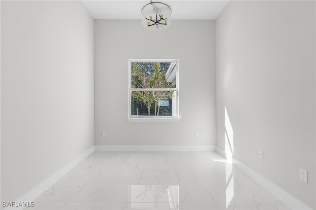 unfurnished room with an inviting chandelier, baseboards, and marble finish floor