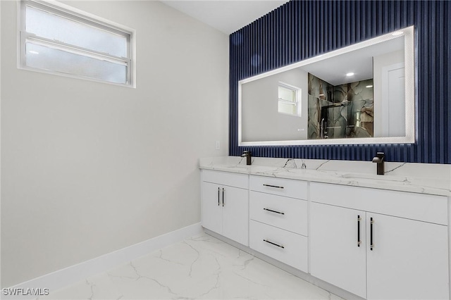 full bath with a wealth of natural light, marble finish floor, baseboards, and a sink