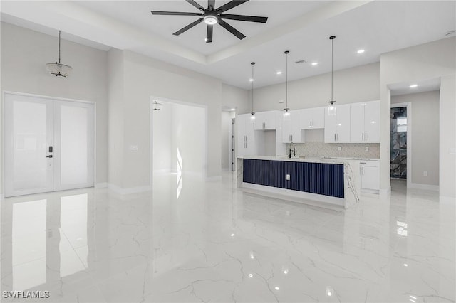 kitchen with a sink, white cabinetry, a ceiling fan, and a towering ceiling