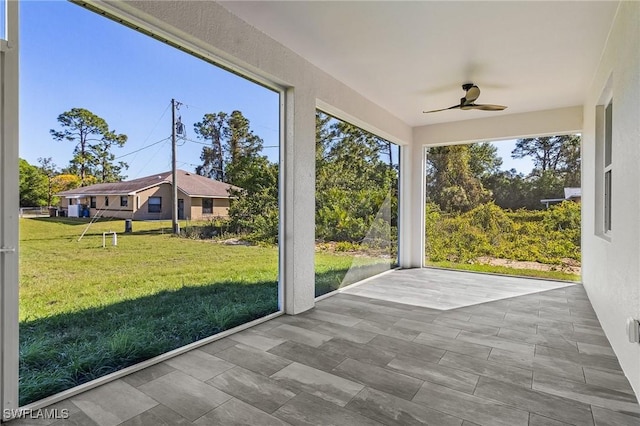 unfurnished sunroom featuring ceiling fan