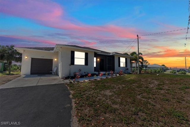 view of front of house with stucco siding, a lawn, an attached garage, and aphalt driveway