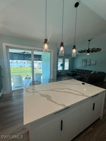 kitchen featuring light stone counters, dark wood-style floors, hanging light fixtures, and white cabinetry