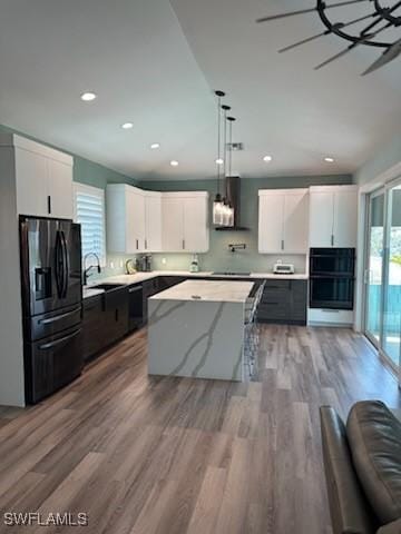 kitchen featuring black appliances, a kitchen island, decorative light fixtures, wood finished floors, and white cabinetry