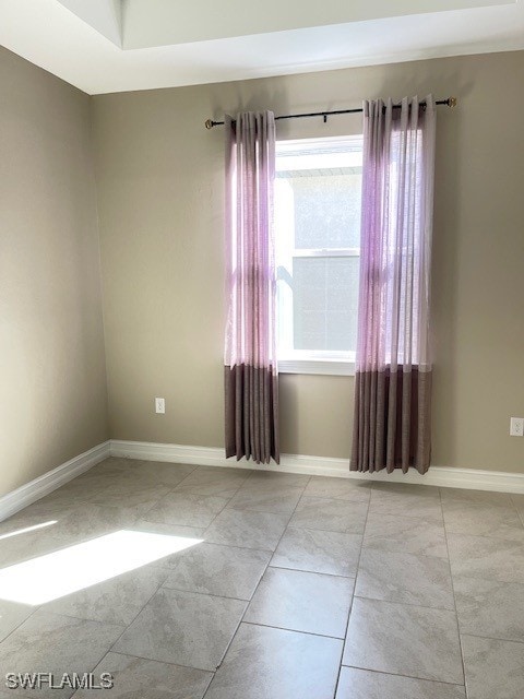 tiled empty room featuring baseboards