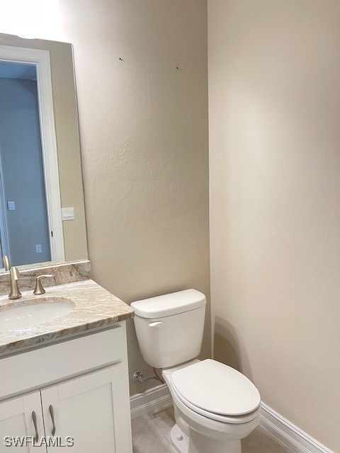 bathroom featuring toilet, vanity, and baseboards