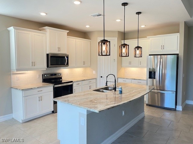 kitchen with pendant lighting, a sink, appliances with stainless steel finishes, white cabinets, and light stone countertops